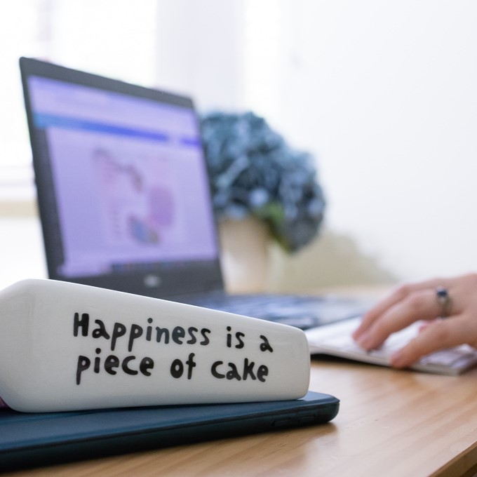 Cake maker reviewing quote email with pricing guide open on screen.